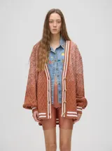 Cardigan tejido de punto con patrón de rombos en degradé de grises y blanco. Tiene corte oversize, mangas largas y cierre frontal con botones.