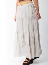 Falda larga de estilo campesino color crudo, confeccionada en algodón italiano con apliques florales al tono. Tiene cintura elastizada y cinto de rafia elastizado desmontable.