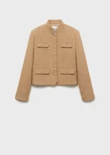 Chaqueta corta color beige de tweed con cuello mao, cierre frontal con botones y cuatro bolsillos de ribete con solapa.