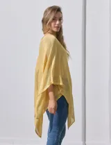 Poncho blanco de tejido calado con lurex, terminación asimétrica y cuello redondo.
