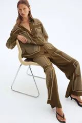 Pantalón de corte recto color marrón con estampado geométrico en blanco. Modelo de tiro alto con elástico en la parte posterior de la pretina y cierre oculto en un lateral.