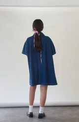 Vestido camisero corto de denim azul, con cuello camisero, mangas cortas y abotonadura frontal.