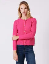 Cardigan tejido color fucsia, con escote a la base y abertura central con botones metálicos dorados. Presenta bolsillos simulados en la parte delantera y terminación desflecada en la abertura y los bolsillos.