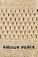 Bolso tote color beige, tejido en paja de papel trenzada, con doble asa corta y texto 'Amour Paris' en negro.