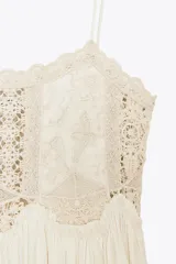 Vestido largo color crudo, de algodón, con tirantes finos y escote recto. Presenta detalle de crochet en la parte superior.