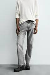 Pantalón de jean celeste de corte flare, con cinco bolsillos, efecto lavado y bajo con acabado irregular.