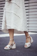 Sandalias de plataforma color blanco, con tiras cruzadas sobre el empeine, pulsera al tobillo con hebilla dorada y taco ancho.