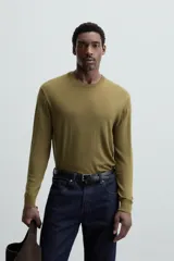 Jersey negro de lana con acabado mercerizado, corte relaxed fit, cuello redondo y mangas largas con terminaciones en rib.