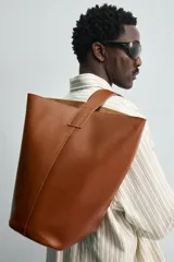 Bolso tipo shopper negro fabricado en piel, con asa de hombro y cierre magnético.