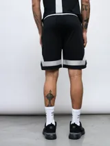 Short deportivo negro de mesh con recortes geométricos en blanco y gris. Logo de Umbro estampado en la pierna izquierda.
