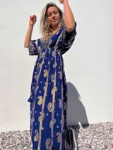 Vestido largo azul con estampado de cachemir dorado, escote en V, mangas cortas y cintura imperio con cordón ajustable.