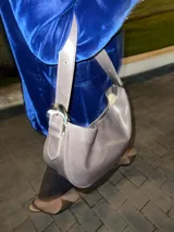 Cartera tipo lady bag color lila, de cuero sintético, con correa ajustable y herrajes metálicos plateados.