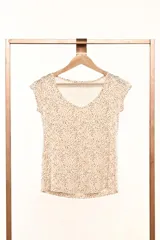Remera blanca con estampado de lunares marrones, corte al cuerpo y mangas cortas.