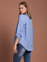 Blusa celeste con escote en V y mangas 3/4 regulables con presilla y botón.