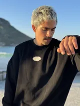 Buzo negro oversize con cuello redondo y logo ovalado bordado en el pecho.
