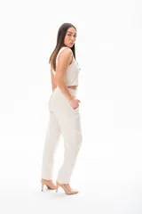 Pantalón de vestir color crudo, de corte recto, con bolsillos laterales y traseros. Se ajusta a la cintura con cinturón de cuero marrón.