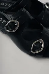 Sandalias planas de cuero color marrón con dos tiras anchas sobre el empeine, cada una con hebilla dorada.