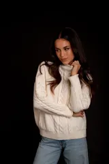 Sweater tejido de punto color rosa pastel, con cuello alto y diseño de trenzas verticales.