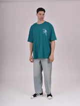 Remera blanca de corte recto con estampado de un auto clásico frente a un skyline urbano.