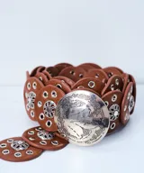 Cinturón marrón con apliques circulares de cuero y detalles metálicos plateados.