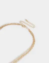 Collar dorado multicadena con dijes de strass con motivos de suerte: herradura, trébol, carta y dado.