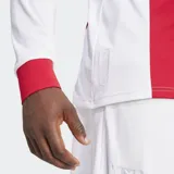 Camiseta de fútbol Adidas de manga larga, inspirada en el primer uniforme del Ajax de Ámsterdam, con diseño que combina un panel central rojo con mangas y costados blancos. Posee cuello de chomba rojo y puños acanalados rojos. En el pecho lleva el escudo conmemorativo del club con las tres cruces de Ámsterdam y el logo de Ziggo.