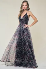 Vestido largo de fiesta con estampado floral en tonos grises, negros y rosados. Tiene escote en V, tirantes finos y falda amplia de organza.