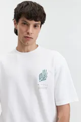 Remera beige de manga corta con textura y corte oversize. Presenta un pequeño bordado en relieve en el pecho.