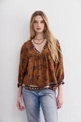 Camisa marrón con estampado floral y lentejuelas, escote en V y mangas largas abullonadas.