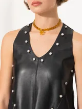 Top negro sin mangas con escote en V, confeccionado en cuero sintético con apliques de perlas.
