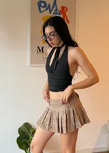 Minifalda marrón a cuadros con pliegues, combinada con un top blanco ajustado.