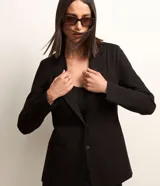 Blazer negro de punto roma con abotonado sencillo, corte entallado y solapas clásicas.