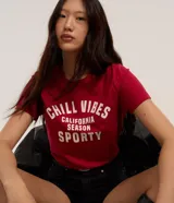 Remera baby look roja de algodón con estampa frontal con la frase "Chill Vibes California Season Sporty" en color blanco.