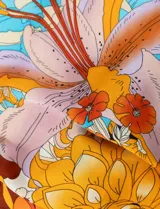 Pañuelo cuadrado de satén estampado con diseño floral en tonos naranja, celeste y lila.