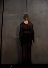 Poncho negro de tejido calado con rayas horizontales.