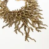 Collar dorado con múltiples cadenas de eslabones y colgantes con forma de ramas.