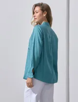 Camisa blanca de lyocell, marca Dash. Tiene cuello con solapa, abertura central con botones, mangas largas regulables con presilla y botón, y dos bolsillos delanteros aplicados.