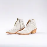 Botines de cuero vacuno color blanco con diseño bordado, taco de madera foliado en cuero de 5cm, cierre del lado interior y horma de punta fina.