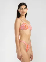 Bikini de dos piezas con estampado animal print en tonos rosado y naranja. El corpiño es de breteles finos y se ata en la espalda. La bombacha es de tiro bajo con cobertura mínima.