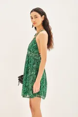 Vestido corto bretelero con estampado reptil en tonos verdes, confeccionado en gasa con lurex y forrería a tono. Cuenta con aplique metálico en el escote, espalda baja con breteles cruzados regulables y elástico en la cintura.