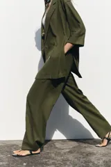 Pantalón color beige de lino, de tiro alto con cintura elástica, bolsillos laterales ocultos en costura y pernera ancha.