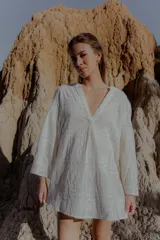 Camisa blanca de broderie con escote en V y mangas largas.