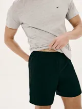 Pijama de dos piezas compuesto por remera manga corta gris con cuello en V y bordado de logo en el pecho, y short negro.