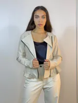 Chaqueta beige de cuero sintético con cierre lateral y volados en la espalda baja.