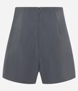Short pollera corto color gris, de sastrería con cierre por cremallera invisible en la parte de atrás, pences y detalle en fruncido en el lateral.