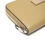 Billetera tipo fichero con cierre perimetral, color beige claro con textura de cuero granulado. Presenta un aplique rectangular central con el logo "XL" en metal plateado.