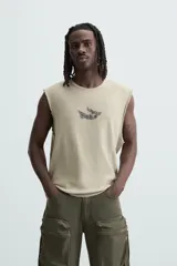 Camiseta sin mangas color arena con cuello redondo y estampado de ave en el pecho.