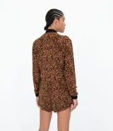 Mono corto con estampado animal print, cuello mao, cierre frontal con cremallera y mangas largas.