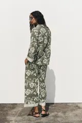 Camisa verde militar con bordado floral blanco, cuello solapa, escote en pico, manga tres cuartos con detalle de guipur y cierre frontal con botones.