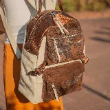 Mochila de cuero vacuno en color arena y cobre, con dos bolsillos frontales y un compartimento principal con cierre, forrada en tela de alta calidad.
